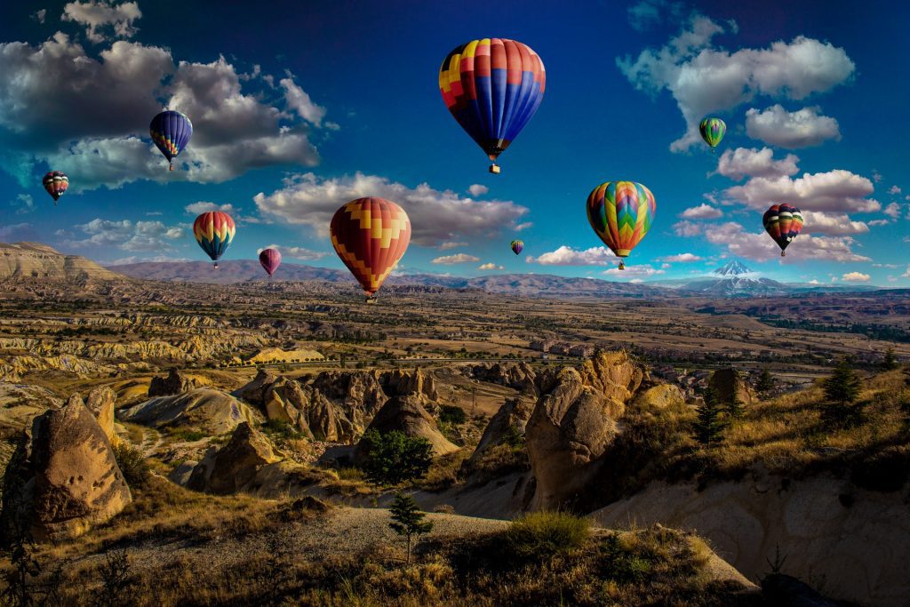 Image of an array of hot air balloons over a rocky rural valley