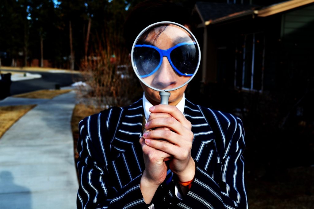 Search for a trademark, trademark clearance, check trademark. Image of a person holding a magnifying glass