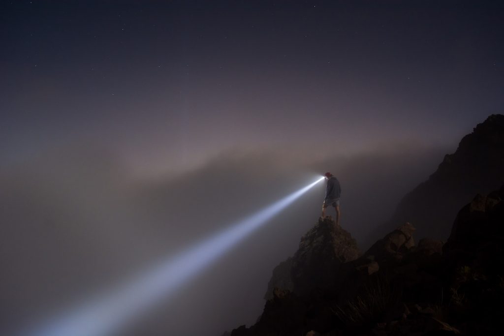 IP due diligence - image of a person on the side of a cliff with a head torch shining it down the hill